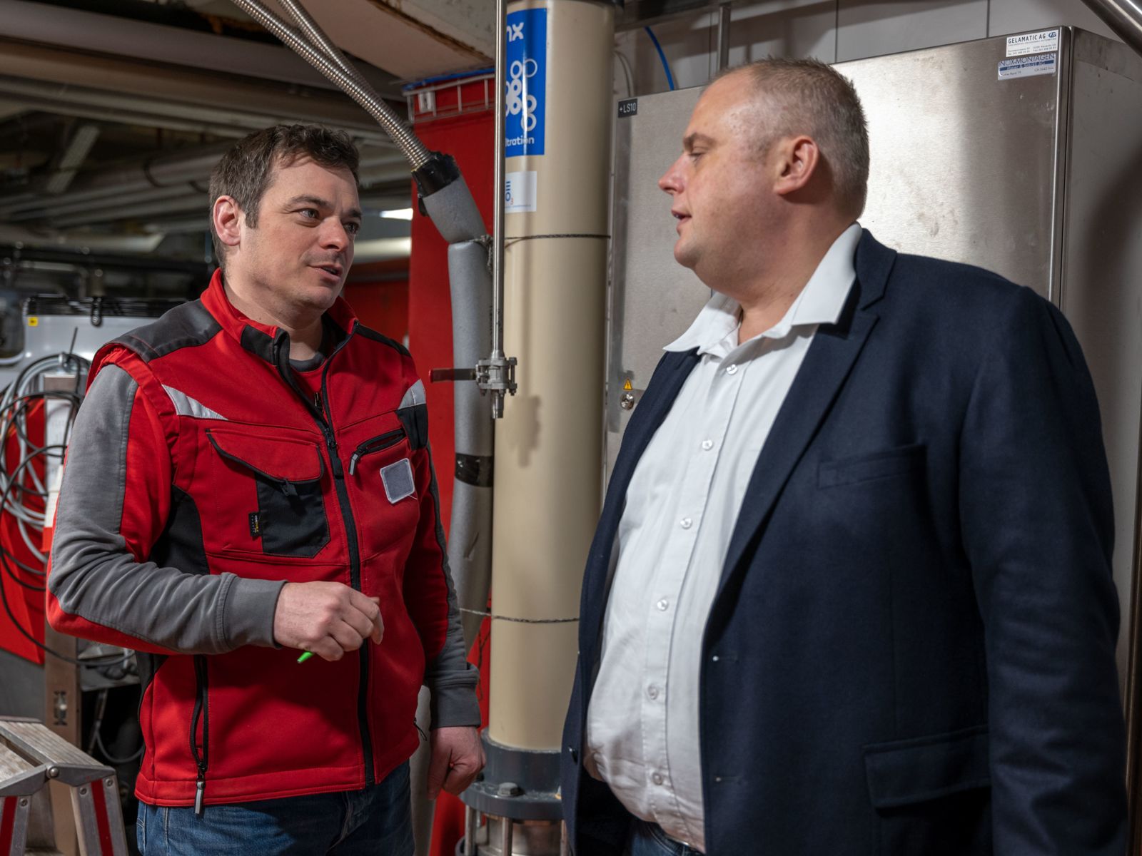 Zwei Männer unterhalten sich in den Räumlichkeiten der Getränkeherstellung von SwissDrink.